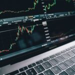 black and silver laptop with stock market display on screen